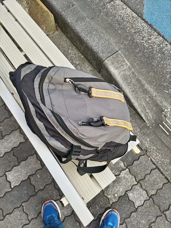 元ニートの齋藤健一が朝の出勤時に白いバス停前のベンチにリュックを置いた様子