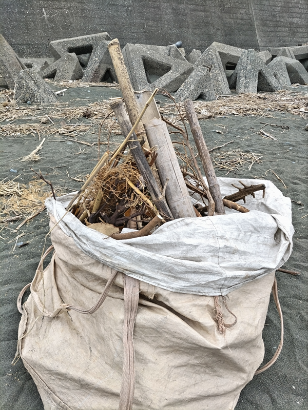 元ニート引籠りの齋藤健一が袋に入れられた乾燥した竹と流木が入った袋を見ている様子