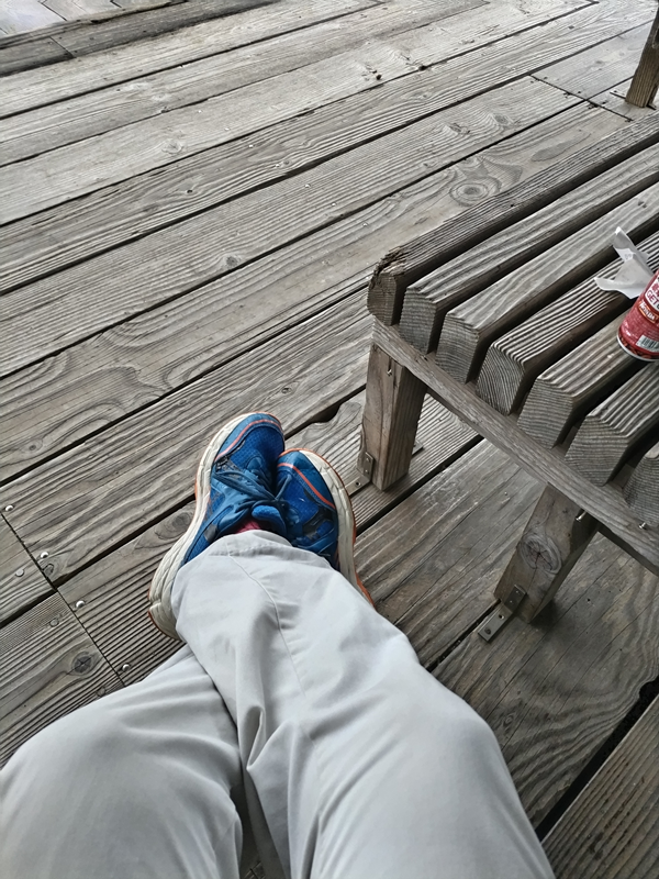 元ニート引籠りの齋藤健一が青いスニーカーを履いて足を交差させている様子