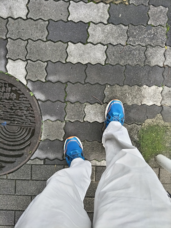 引籠りニートだった齋藤健一が青いスニーカーを履いて歩道を歩いている時の様子