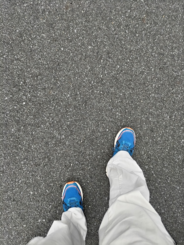 元ニート引籠りの齋藤健一が青いスニーカーを履いて雨で濡れたアスファルトの地面を歩いている時の様子