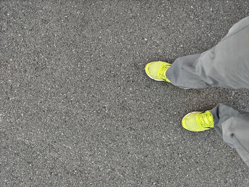 引籠りニートだったセル齋藤が黄色いスニーカーを履いてアスファルトの地面に立っている様子