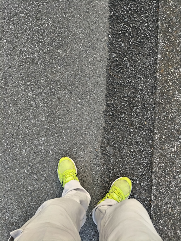 元引籠りニートだった齋藤健一が黄色いスニーカーを履いてアスファルトの道路を歩いている様子