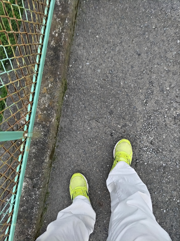 元引籠りが黄色いスニーカーを履いてアスファルトの地面を踏んでいる様子