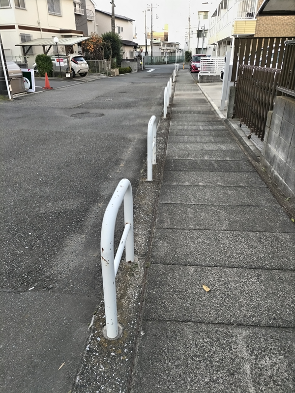 引籠りニートだった齋藤健一が白い柵の中のコンクリートの歩道を見つめている様子
