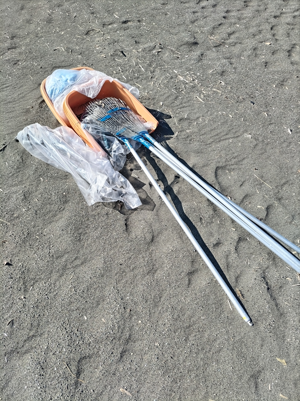 元引籠りニートの齋藤健一が大磯町の砂浜に置かれた海岸清掃用具を見つめている様子