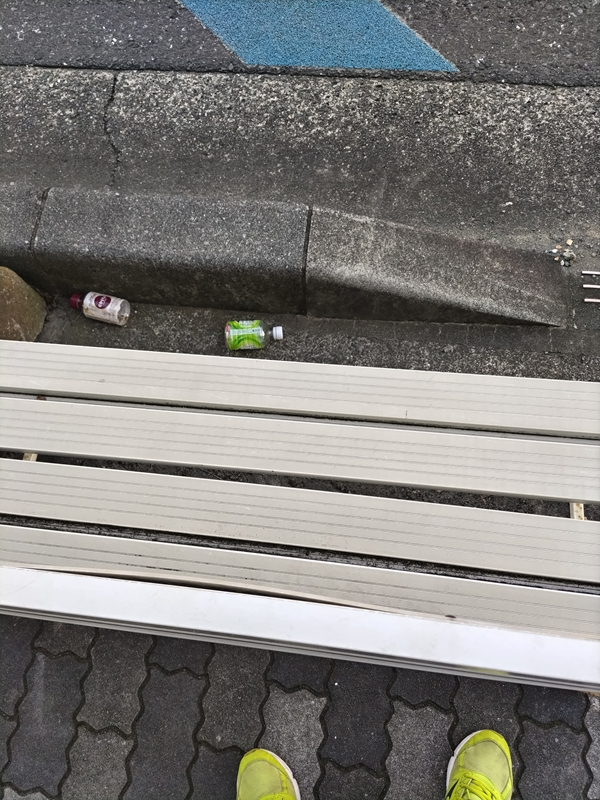 引籠りニートだった齋藤健一が白いベンチ前に落ちているゴミのペットボトルを見ている様子