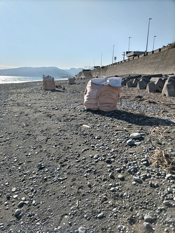 引籠りだった齋藤健一が海岸漂着ゴミで一杯になったゴミ袋を見ている様子