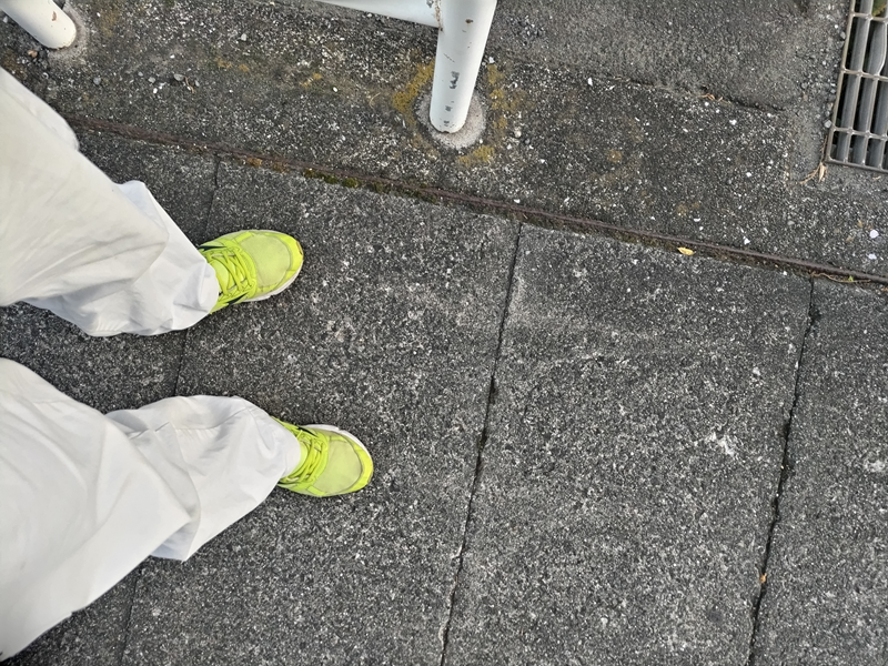 元ニートだったセル齋藤が黄色い靴と白い作業靴の服装でコンクリートの地面に立っているところ